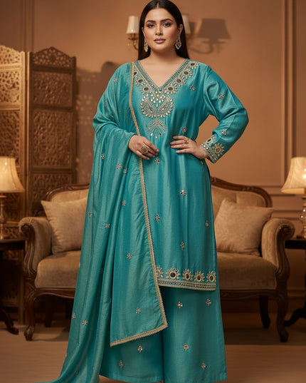 A turquoise blue traditional outfit set hanging on wooden hangers against a dark background. The set includes a long kurta with ornate gold and silver embroidery and mirror work, and matching wide-leg pants.