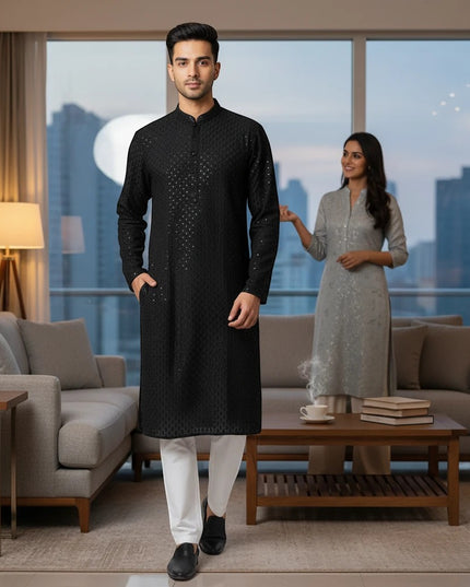 Kurti Connection USA black embroidered kurta with mandarin collar worn by a man with white trousers in a living room.