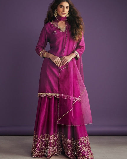 Kurti Connection USA magenta silk sharara suit with gold embroidery and sheer dupatta. Model wears ornate earrings and bracelet.
