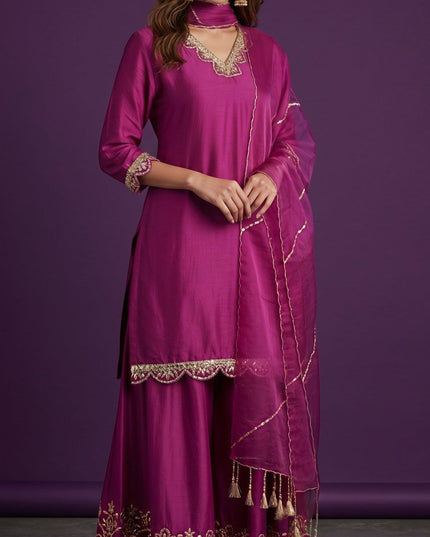 Kurti Connection USA magenta silk sharara suit with gold embroidery on neckline, sleeves, and hem. Includes dupatta with tassels.
