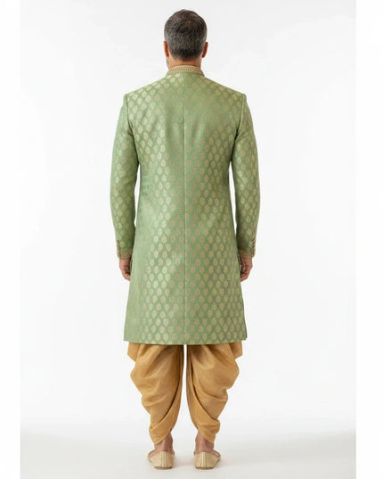 Back view of a man wearing a Kurti Connection USA sage green sherwani with golden motifs and a matching gold dhoti.