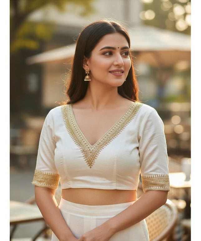 Kurti Connection USA white ethnic blouse with V-neck, gold embroidery, and half-sleeves worn by a woman outdoors.